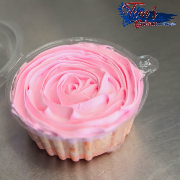A plastic container holds a dessert with pink frosting swirled like a rose, from Tom's Cuban on the Go.