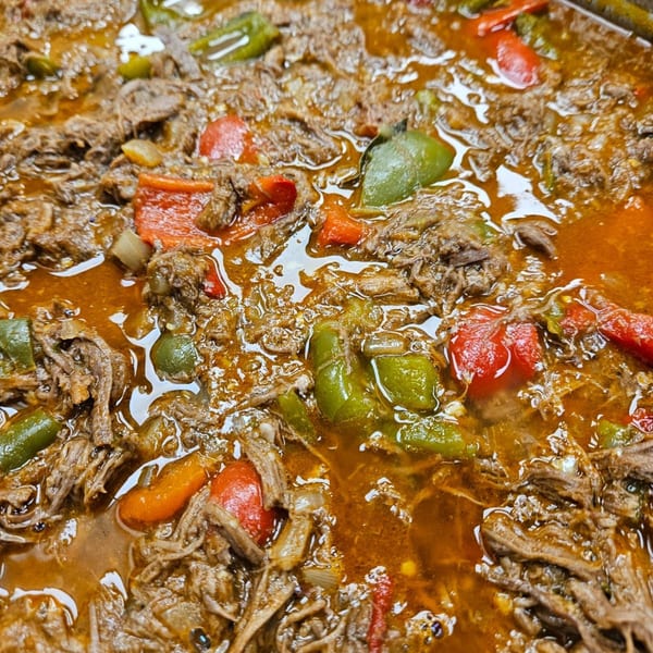 Close-up of Ropa Vieja, shredded beef stew with red and green bell peppers in a rich sauce.
